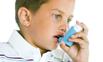 Young boy using an inhaler for treatment of asthma