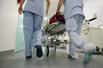 Two nurses pushing hospital trolley down corridor
