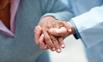 A health professionals hand steadying and elderly womans hand