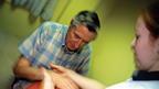 Man after a stroke having physiotherapy on his hands