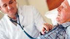 Elderly in man in bed with health worker tending to him