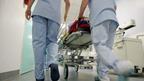 Two nurses pushing hospital trolley down corridor