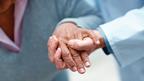 A health professionals hand steadying and elderly womans hand