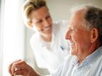 Elderly man in wheelchair with smiling healthcare worker