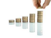 A hand pinching coins from a pile of pound coins