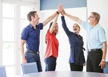 Four people in management meeting high fiving