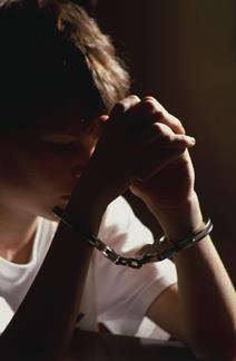 Young offender wearing handcuffs in police custory