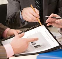 A meeting underway with hands pointing at graph data