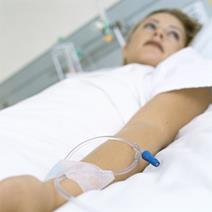 A woman lying in a hopistal bed with drip in her arm