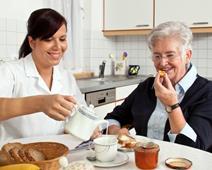 A community carer helps an older person with breakfast