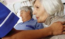 Man in hospital bed with unhappy woman and nurse at his side