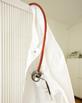 A doctor's coat hanging on door, with a stethoscope