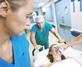 medical staff wheeling a patient on a gurney through a ward