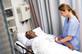 Nurse tending to patient in hospital bed