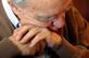 Older man leaning on walking stick possibly asleep