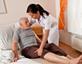 Nurse helping patient into bed at home
