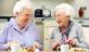 Two older women eating roast dinner with cups of tea, laughing