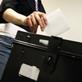 Voter placing vote into ballot box