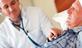 Elderly in man in bed with health worker tending to him