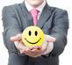 A suited man holding a smiley face stress ball