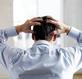 A stressed man with hands on his head
