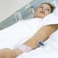 A woman lying in a hopistal bed with drip in her arm