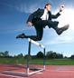 Man in suit jumping hurdle